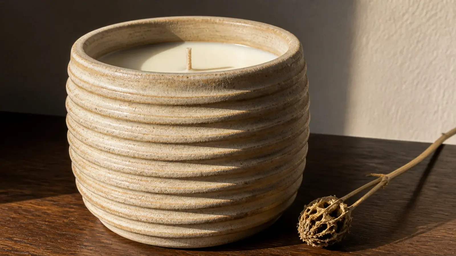 ribbed sand colored stoneware vessel candle catching raking afternoon light