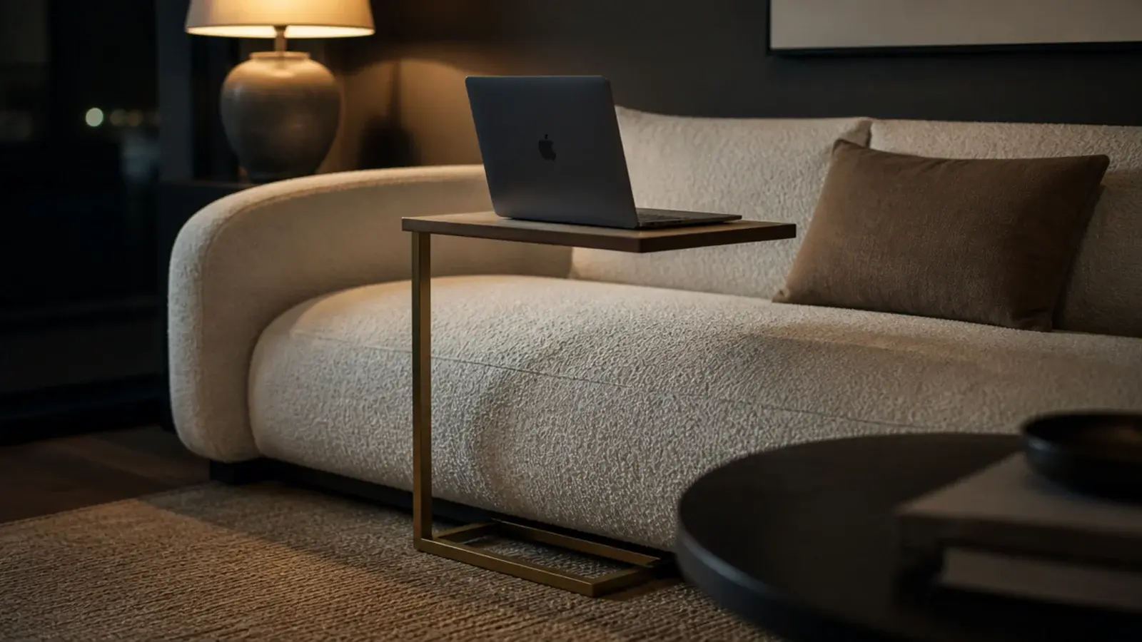 narrow C table tucked beside a sofa arm holding a laptop and mug