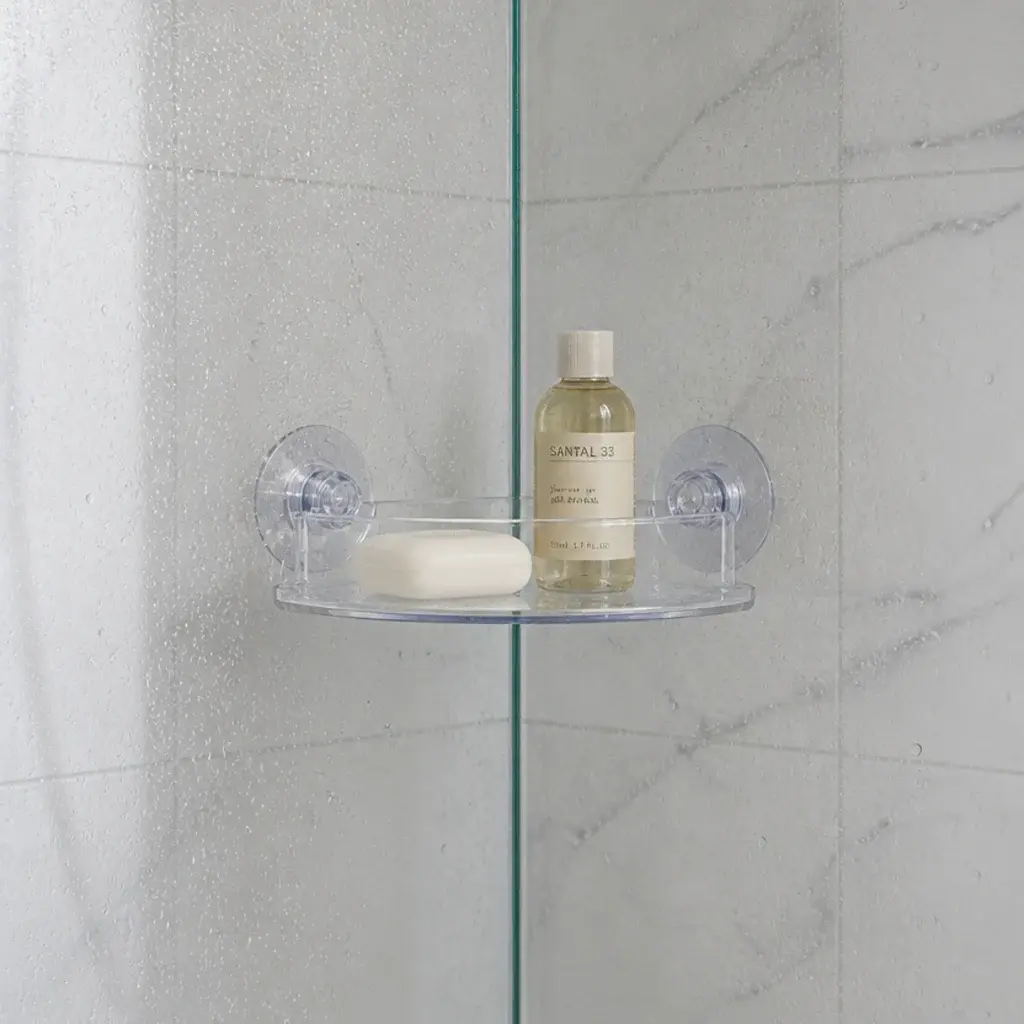 clear suction mounted corner shelf on shower glass holding soap