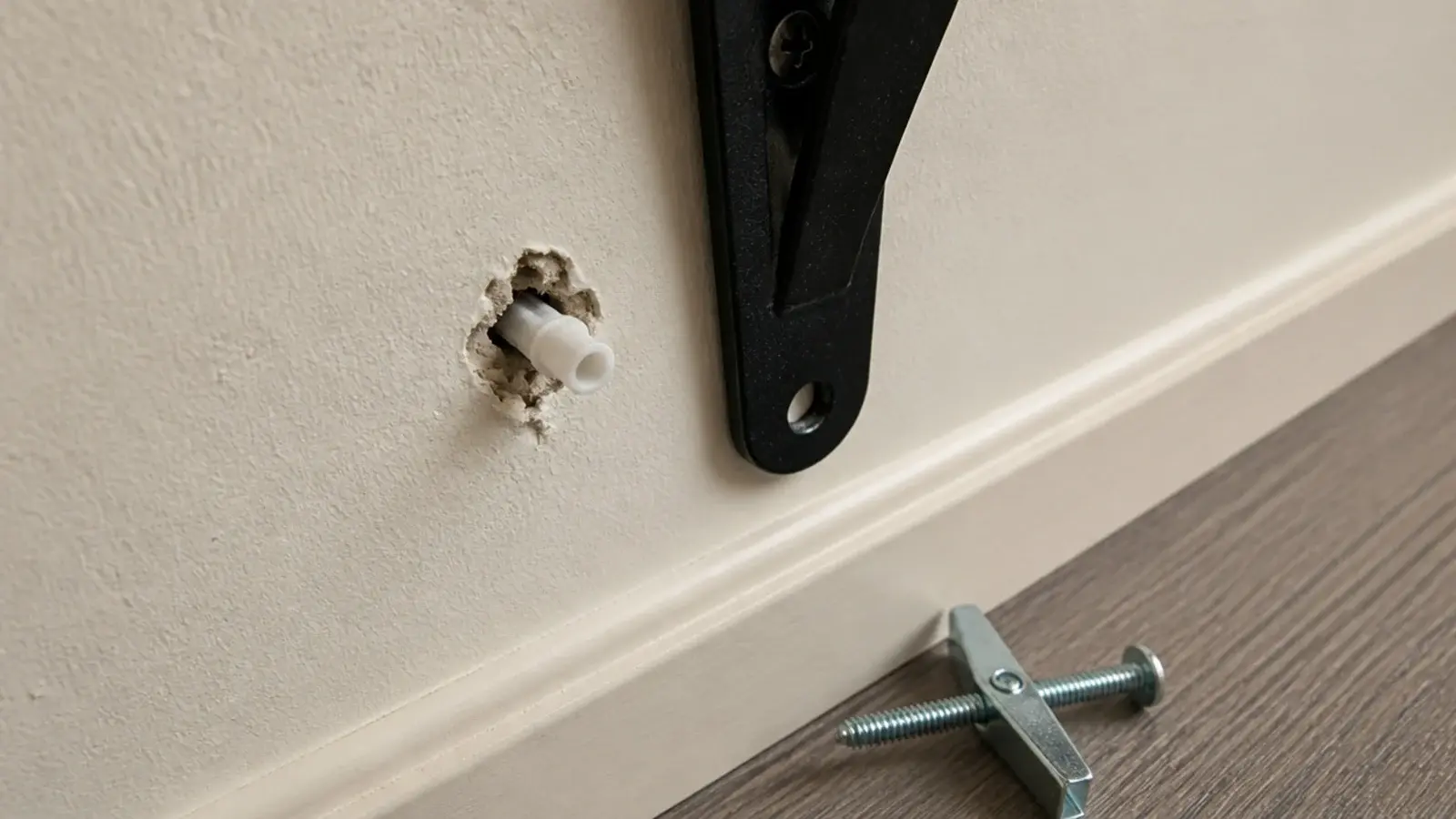 plastic wall plug pulled loose from drywall beside a corner shelf bracket