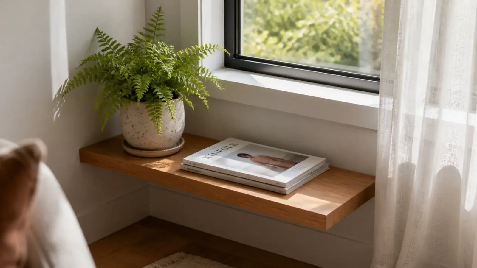 low floating shelf beneath a corner window holding a fern and books