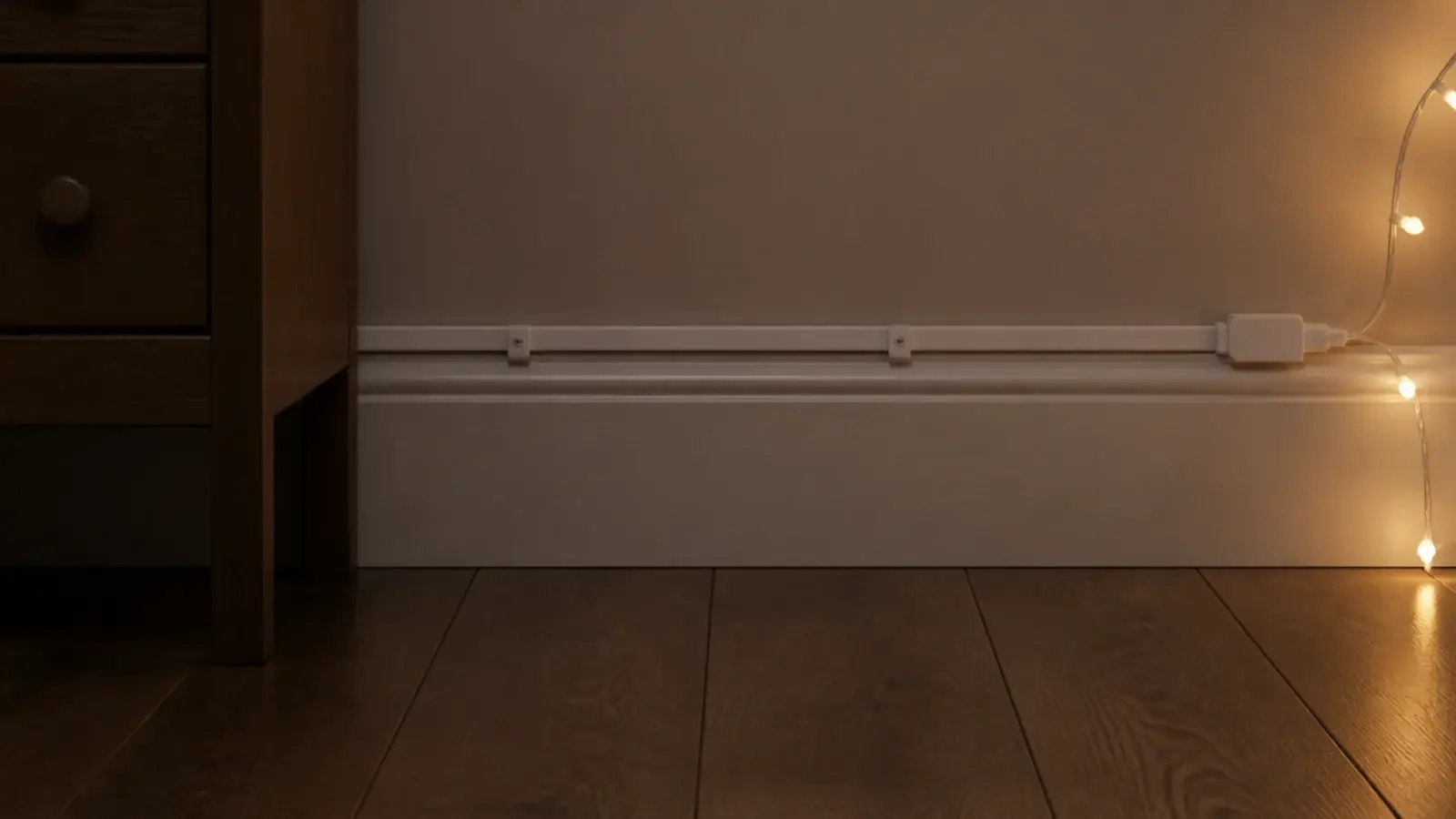 flat extension lead running along a skirting board behind furniture