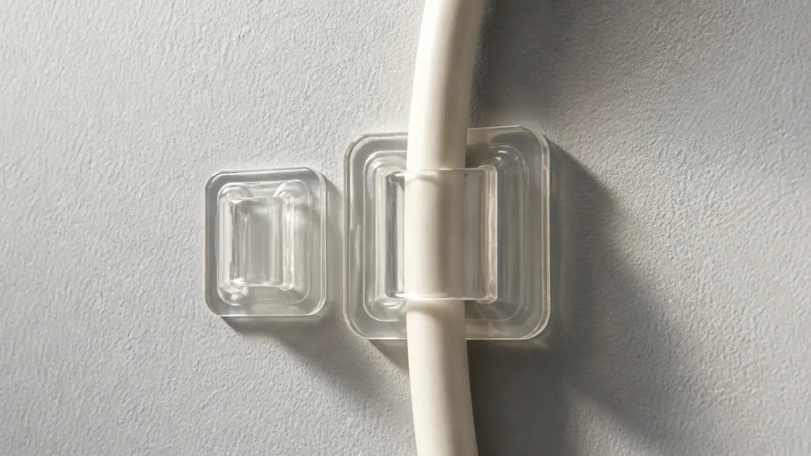 two sizes of adhesive clip compared on a painted wall