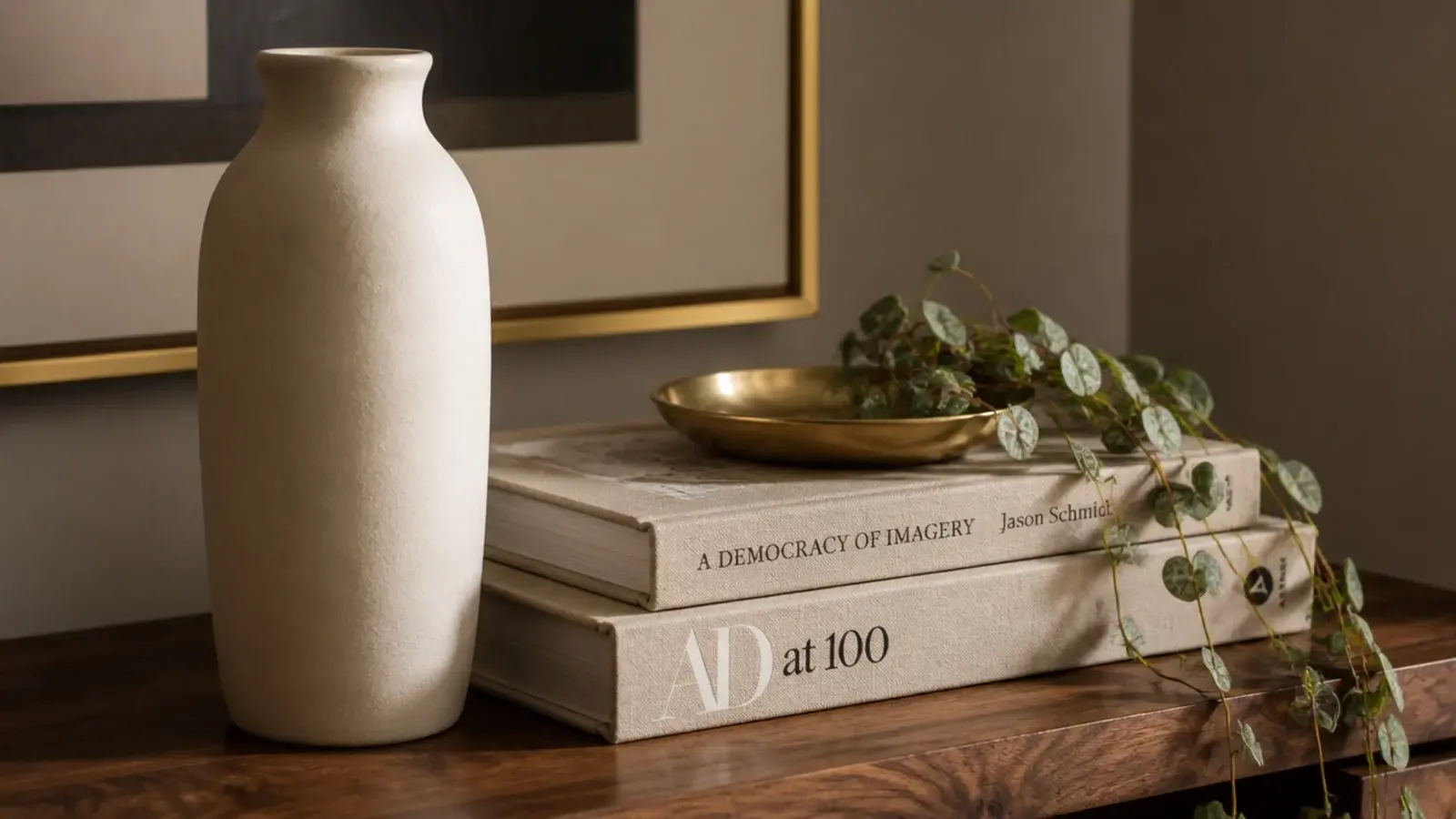 shelf vignette of a tall vase stacked books and a small trailing plant