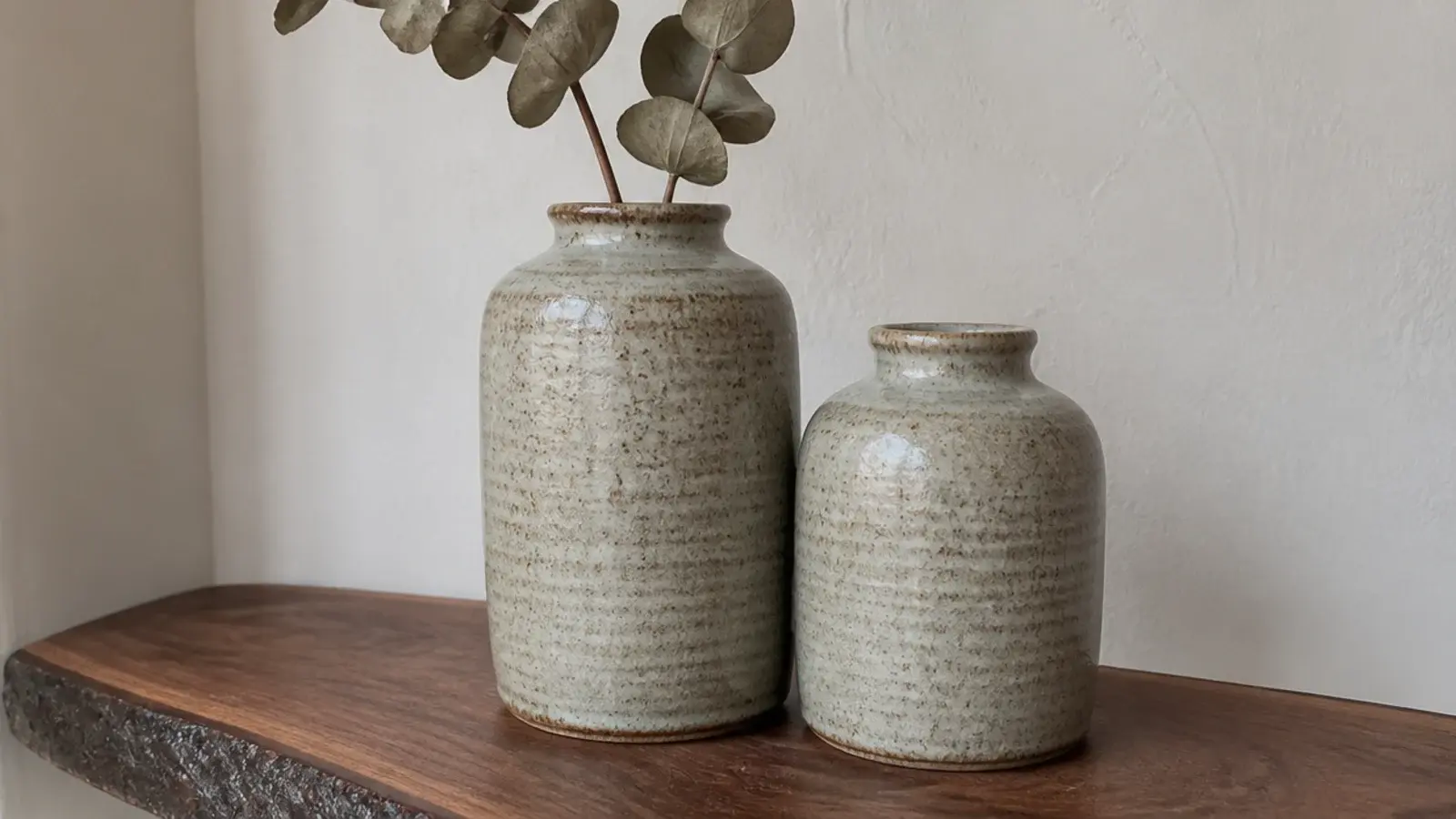 two stoneware jars of different sizes paired together on a shelf