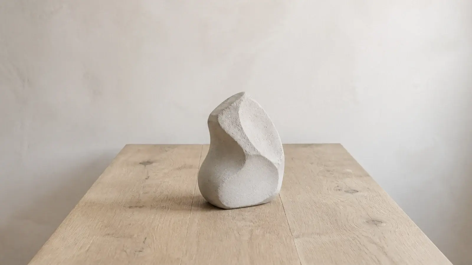 single sculptural stone object alone on an otherwise empty wooden shelf