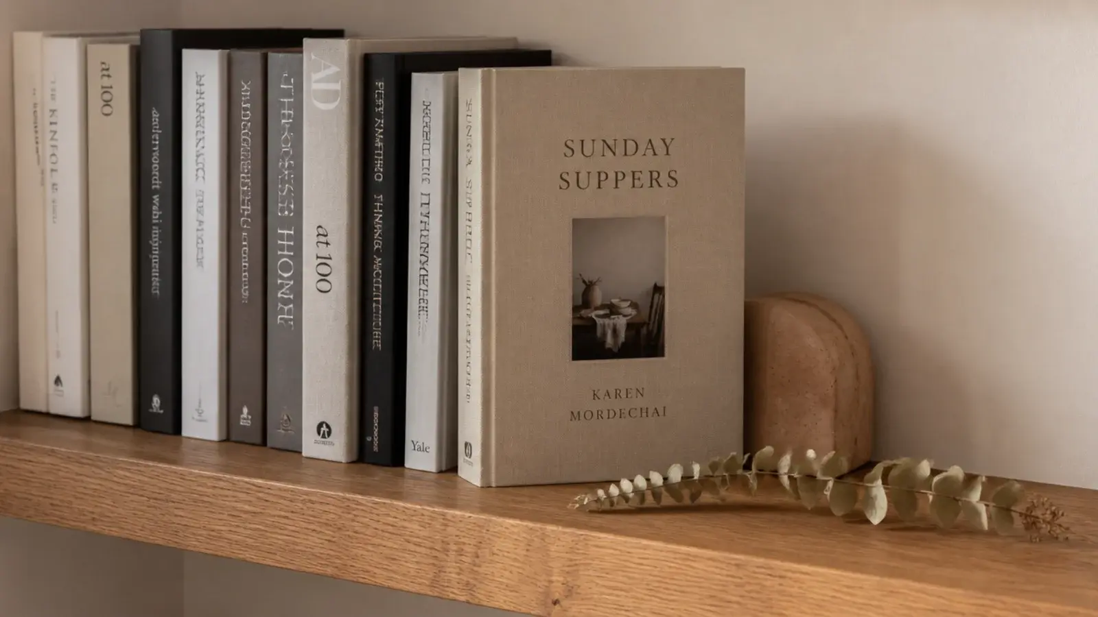 one book turned cover out among spines on a wooden floating shelf