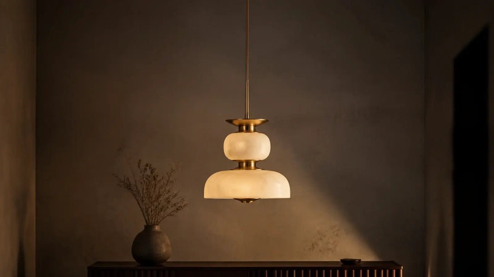 tall view of a sculptural ceiling hanging light above a plaster wall