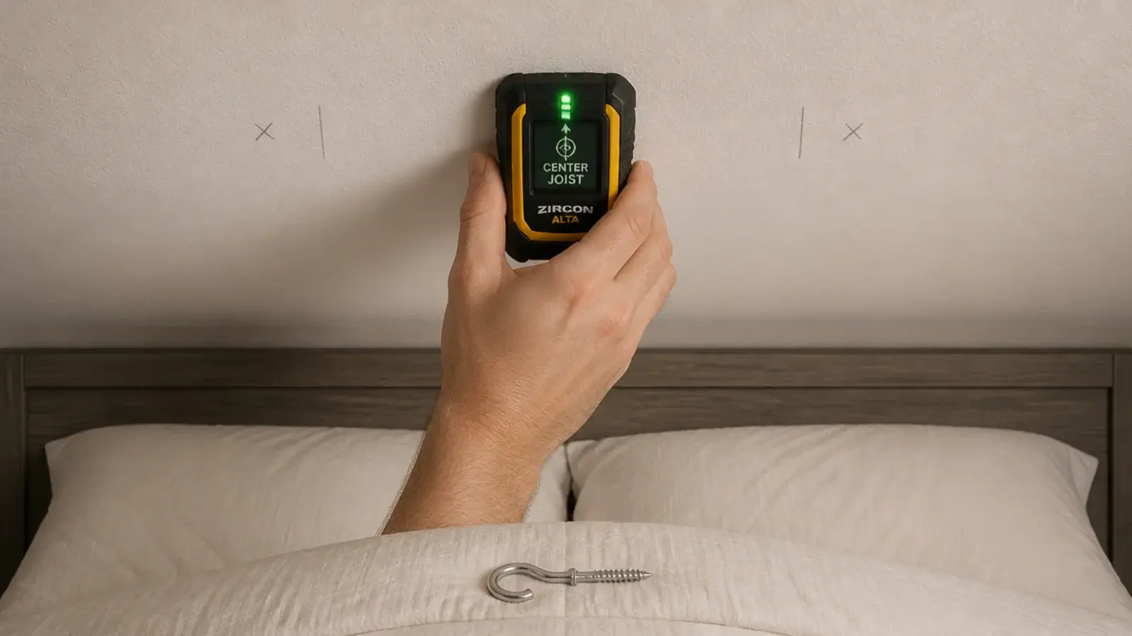 stud finder held against a bedroom ceiling above a bed