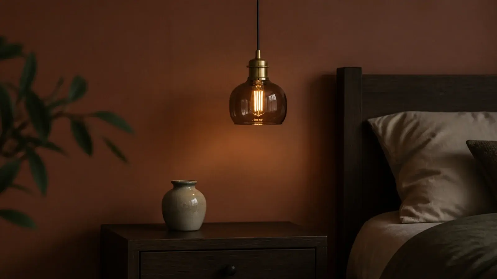 smoked glass pendant with brass fittings against a deep painted wall