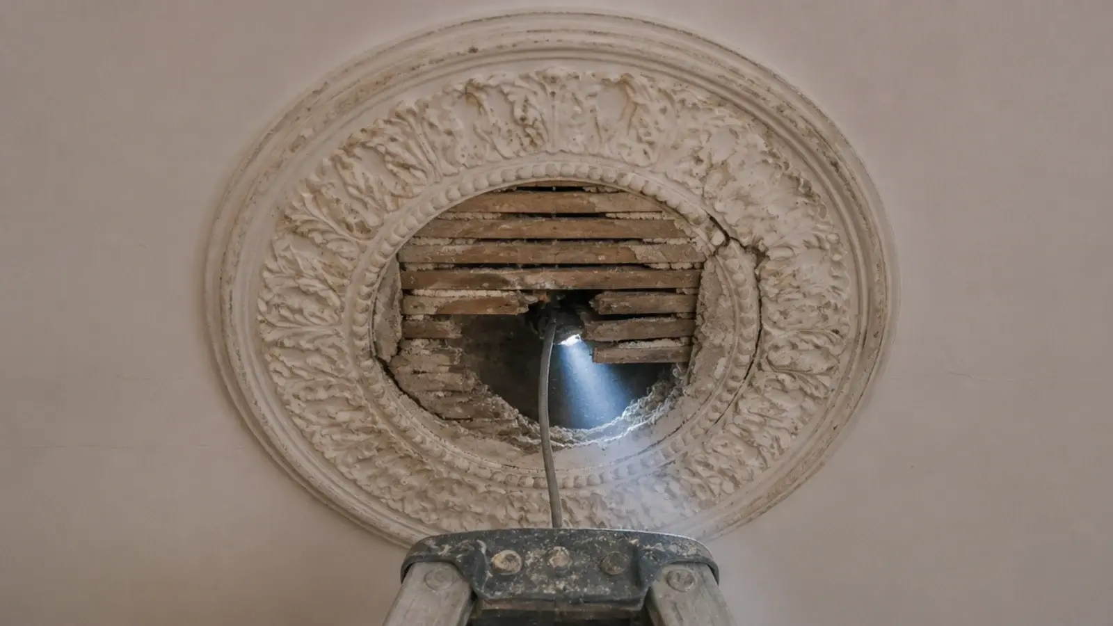 old ceiling rose opened to show thin lath and plaster behind