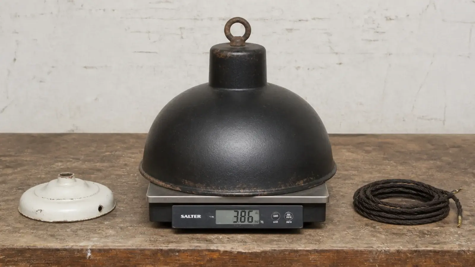 heavy iron shade resting on scales beside an old ceiling rose