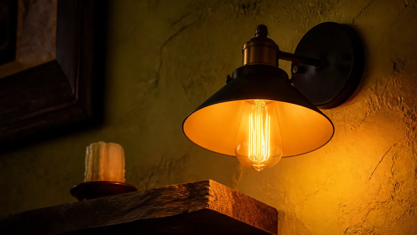 very warm amber bulb glowing against rough plastered wall