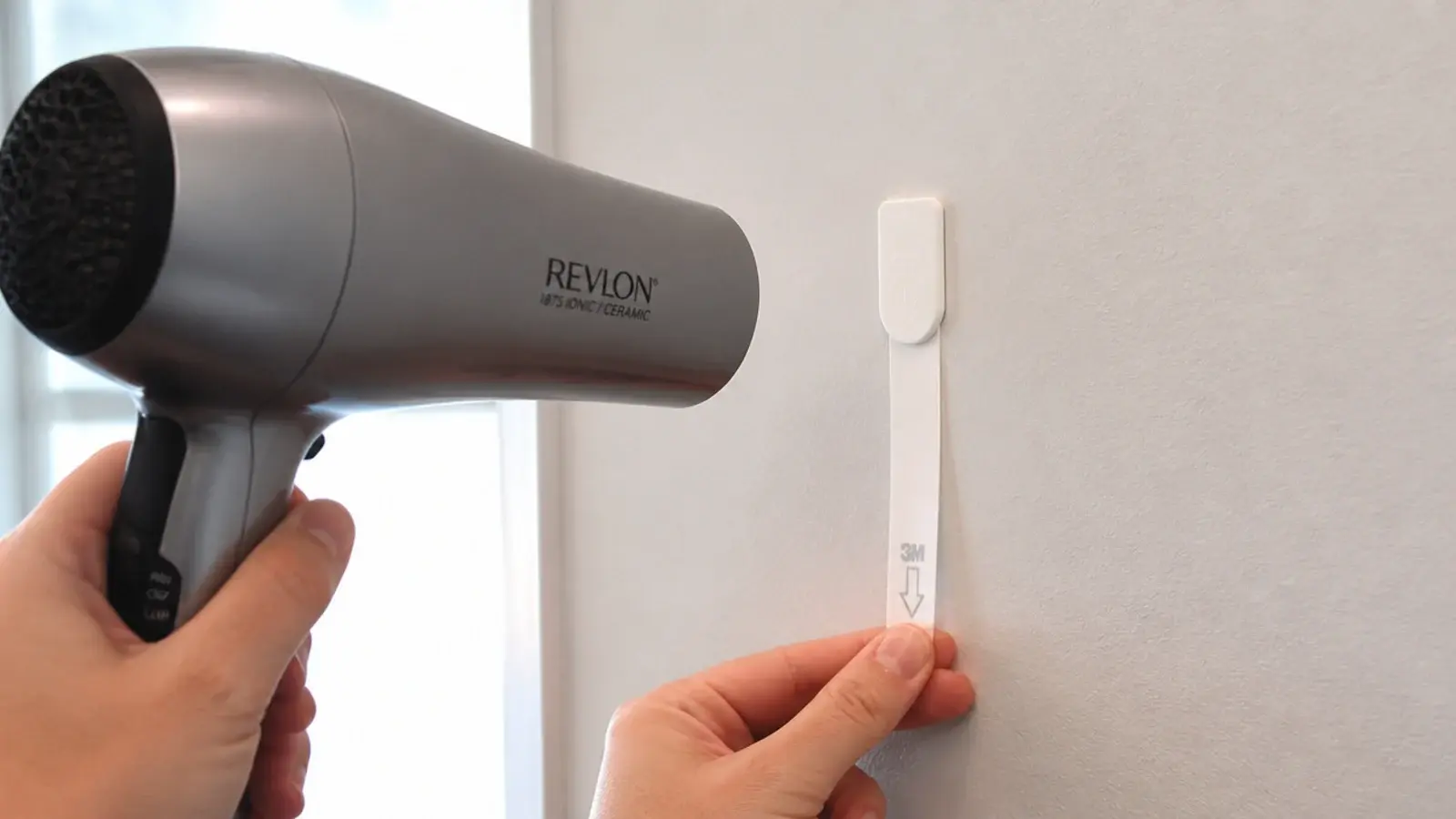 hair dryer warming an adhesive strip before careful removal