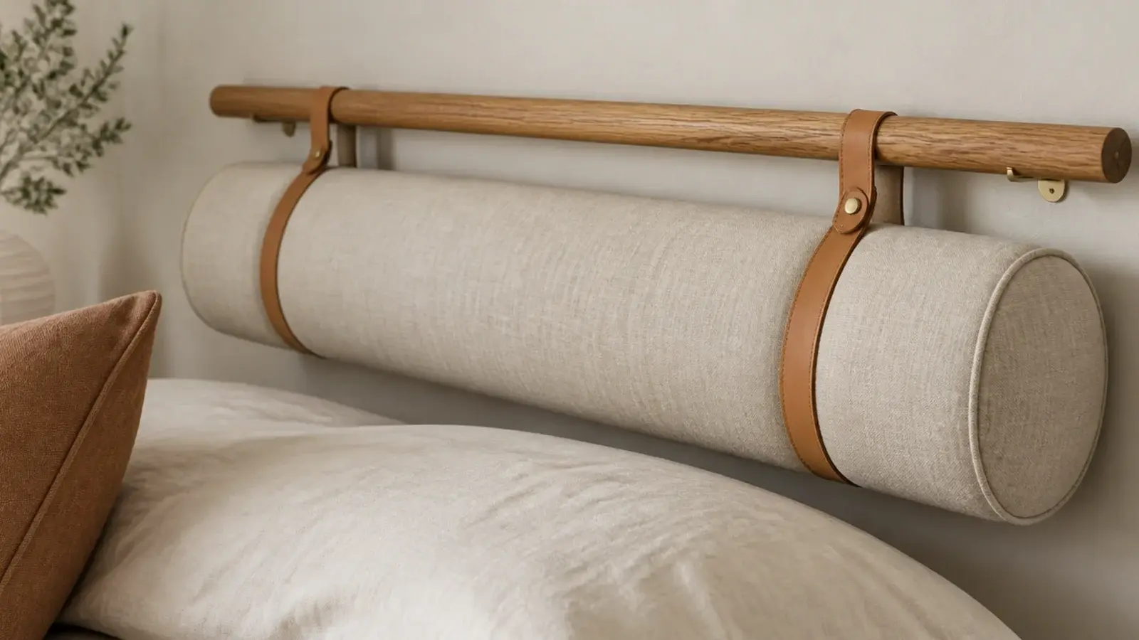 long linen bolster tied to a slim wall rail with leather straps