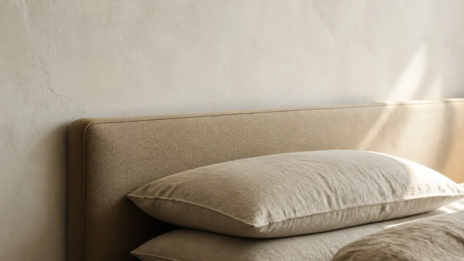 low profile headboard rising just above stacked pillows in a small room
