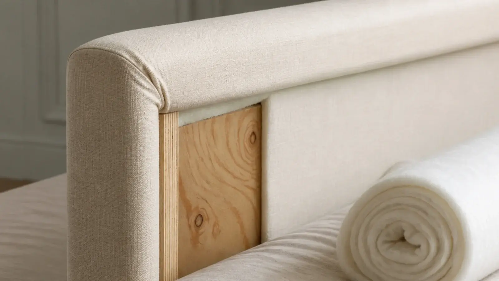 thin padded headboard panel showing hard plywood beneath the fabric