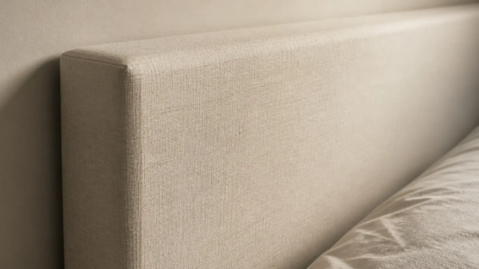 foam edges showing sharply through the linen of a headboard panel