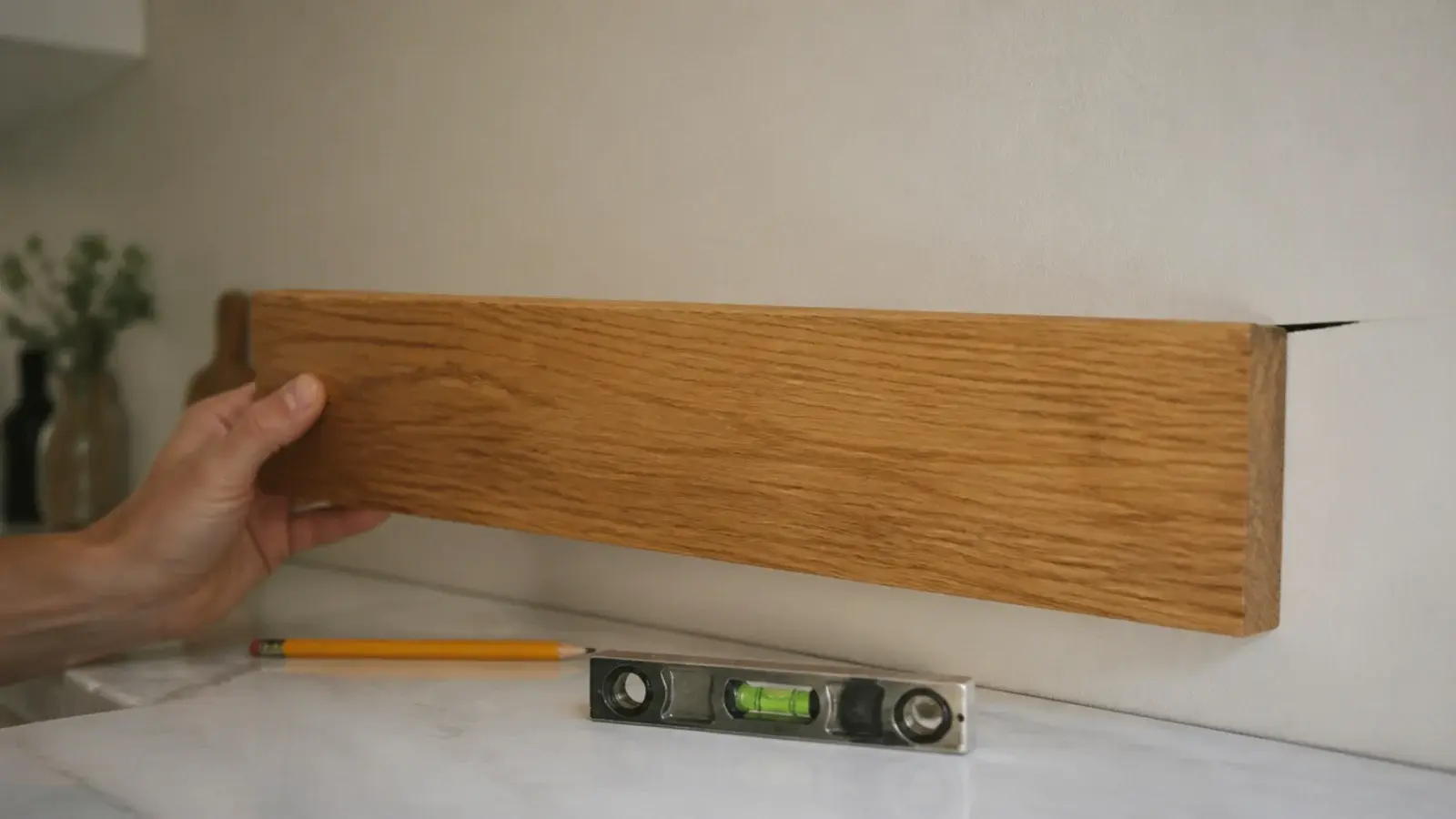 oak shelf board held against a kitchen wall showing a gap behind it