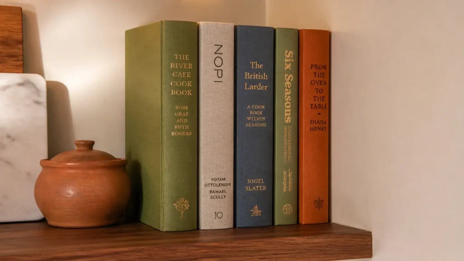 row of cookbooks held upright at the end of a kitchen shelf run