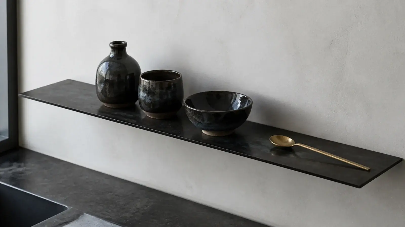 thin blackened steel plate shelf on a modern kitchen wall with ceramics