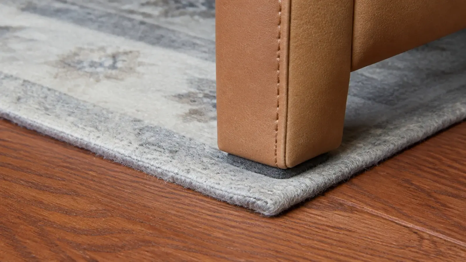 leather chair leg standing squarely on a rug corner to hold it flat