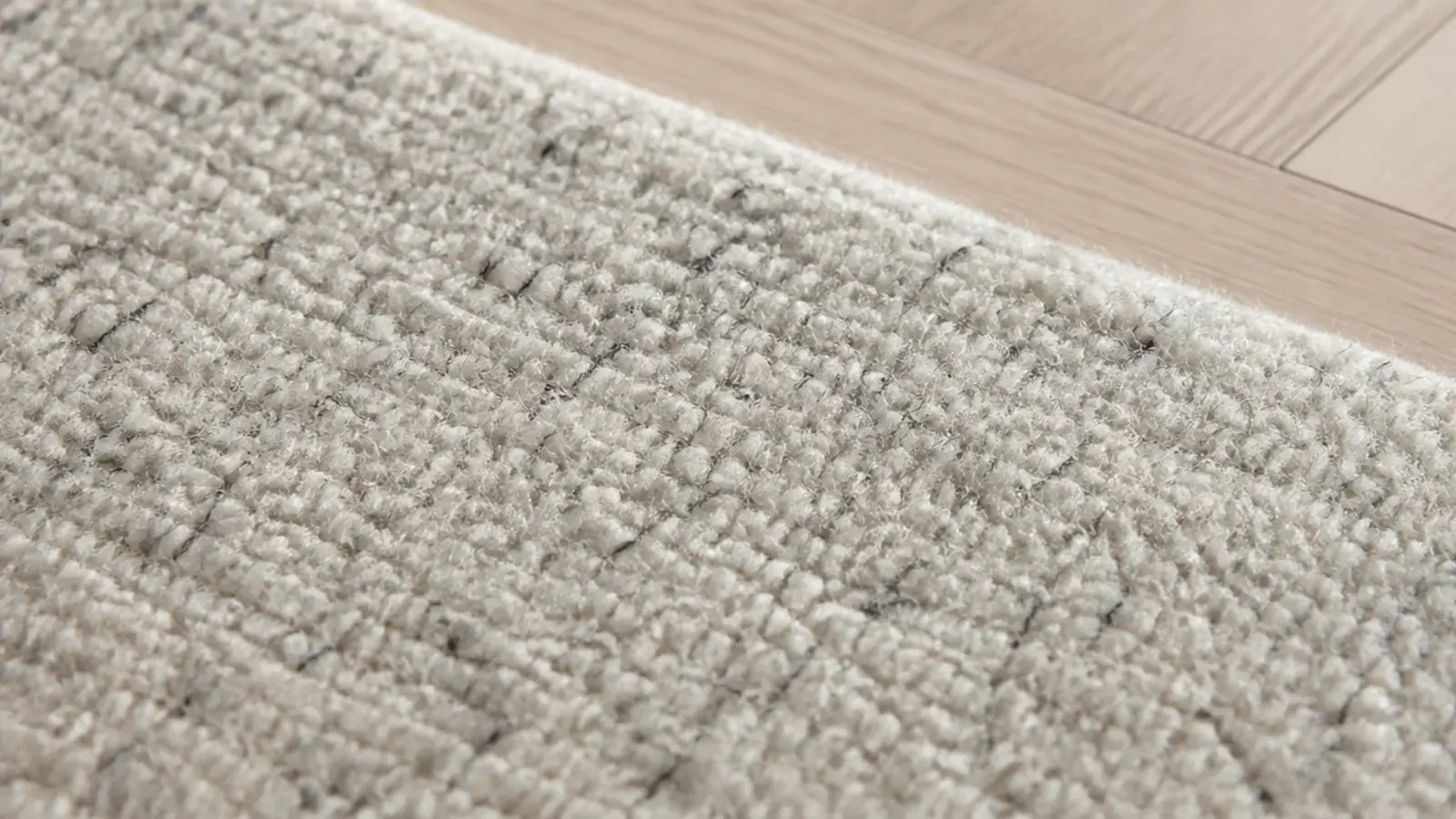 pale wool rug flecked with fine charcoal fibres across the pile