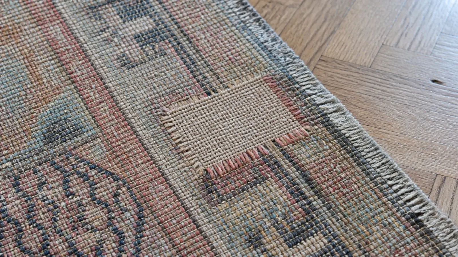 small reweave patch visible from the back of an old wool rug