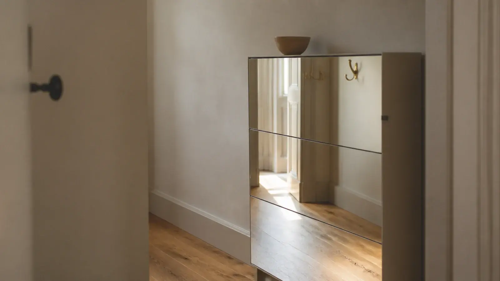 mirrored front shoe cabinet reflecting daylight down a windowless hall