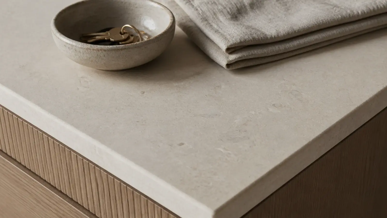 honed stone top on a modern shoe cabinet holding a stoneware key bowl