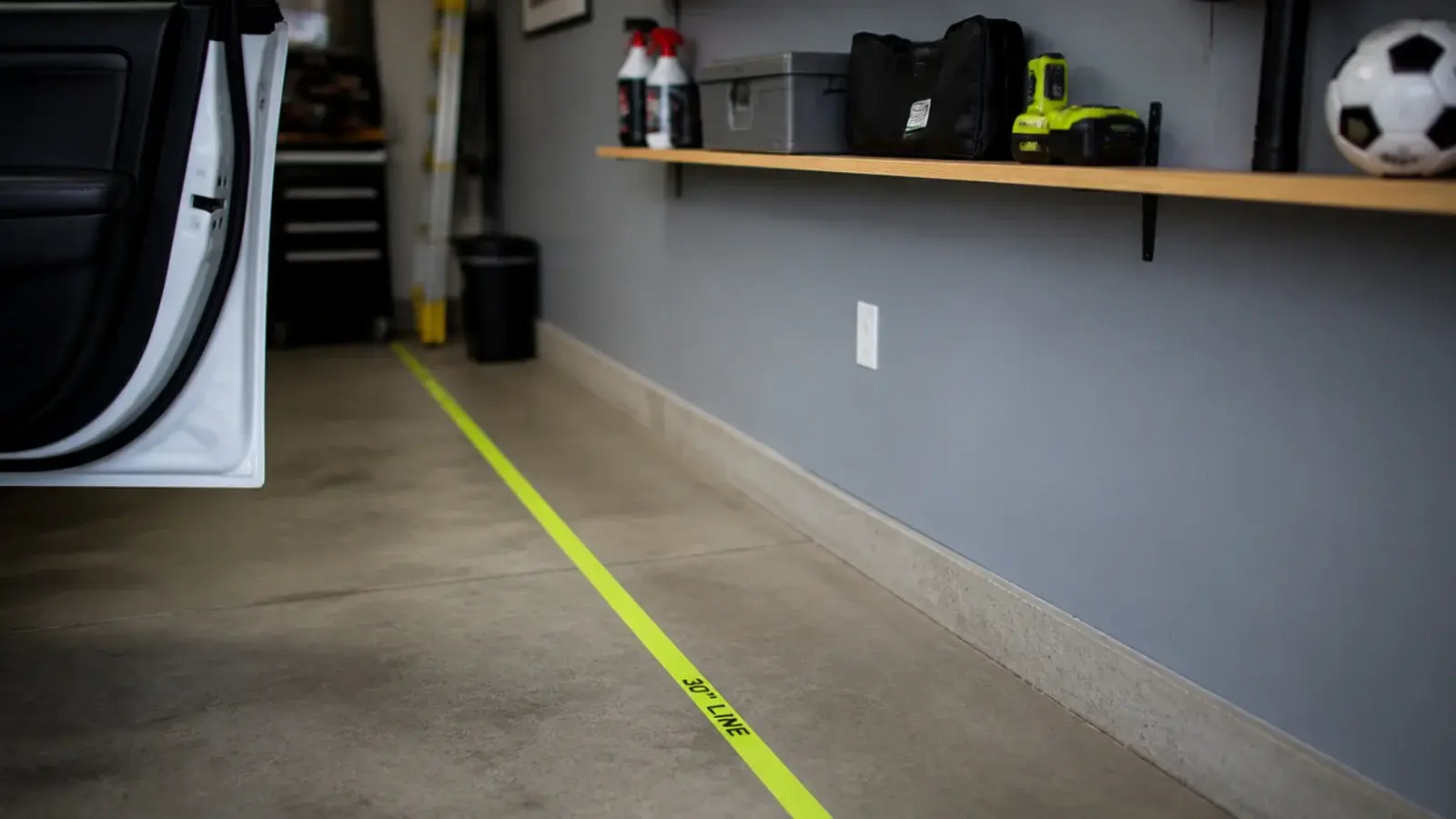 garage shelving with tape marking clear floor space beside a car door