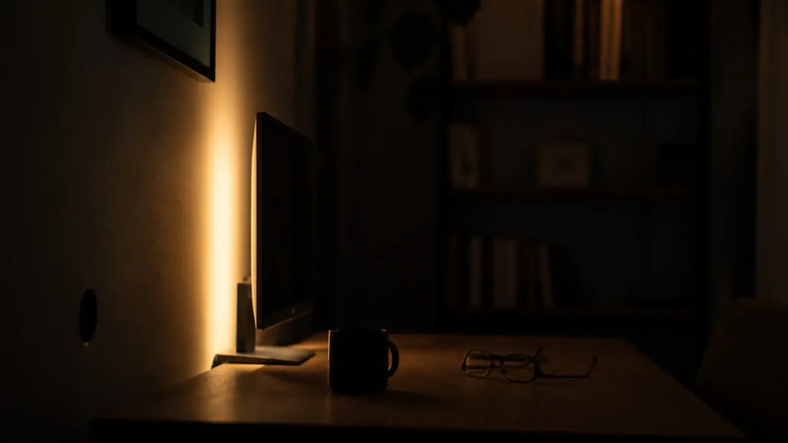 soft glow behind a monitor washing a pale wall in warm light