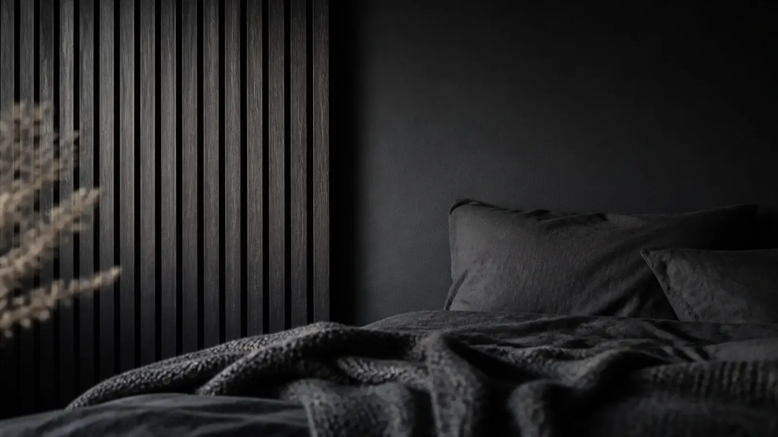 black bedroom wall with slatted timber panel and matte textiles