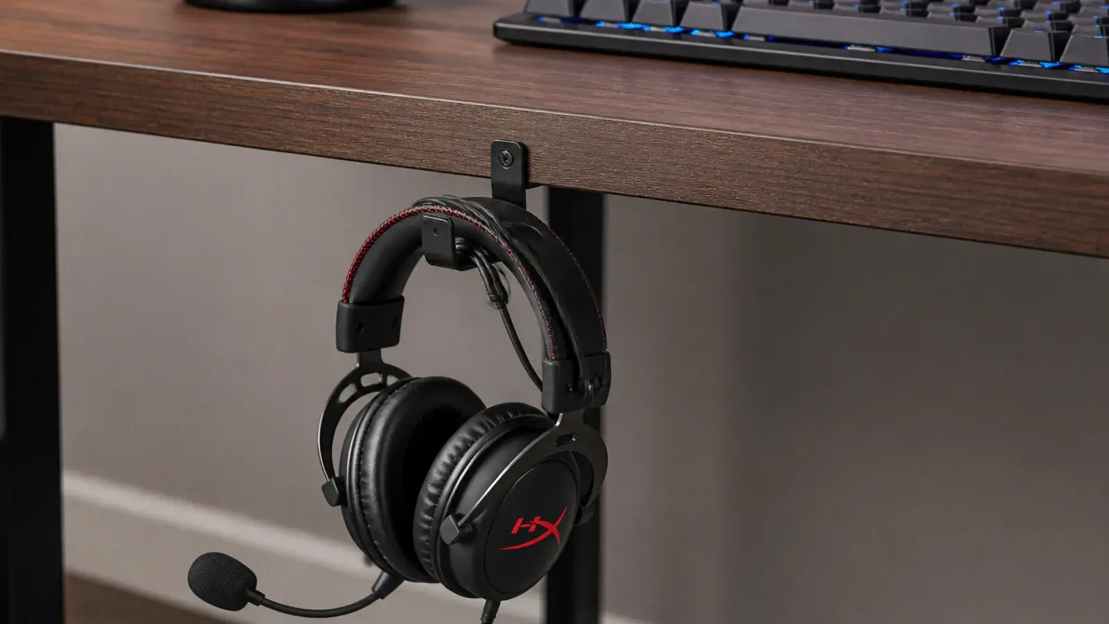headset hanging from an under desk hook above a clear surface