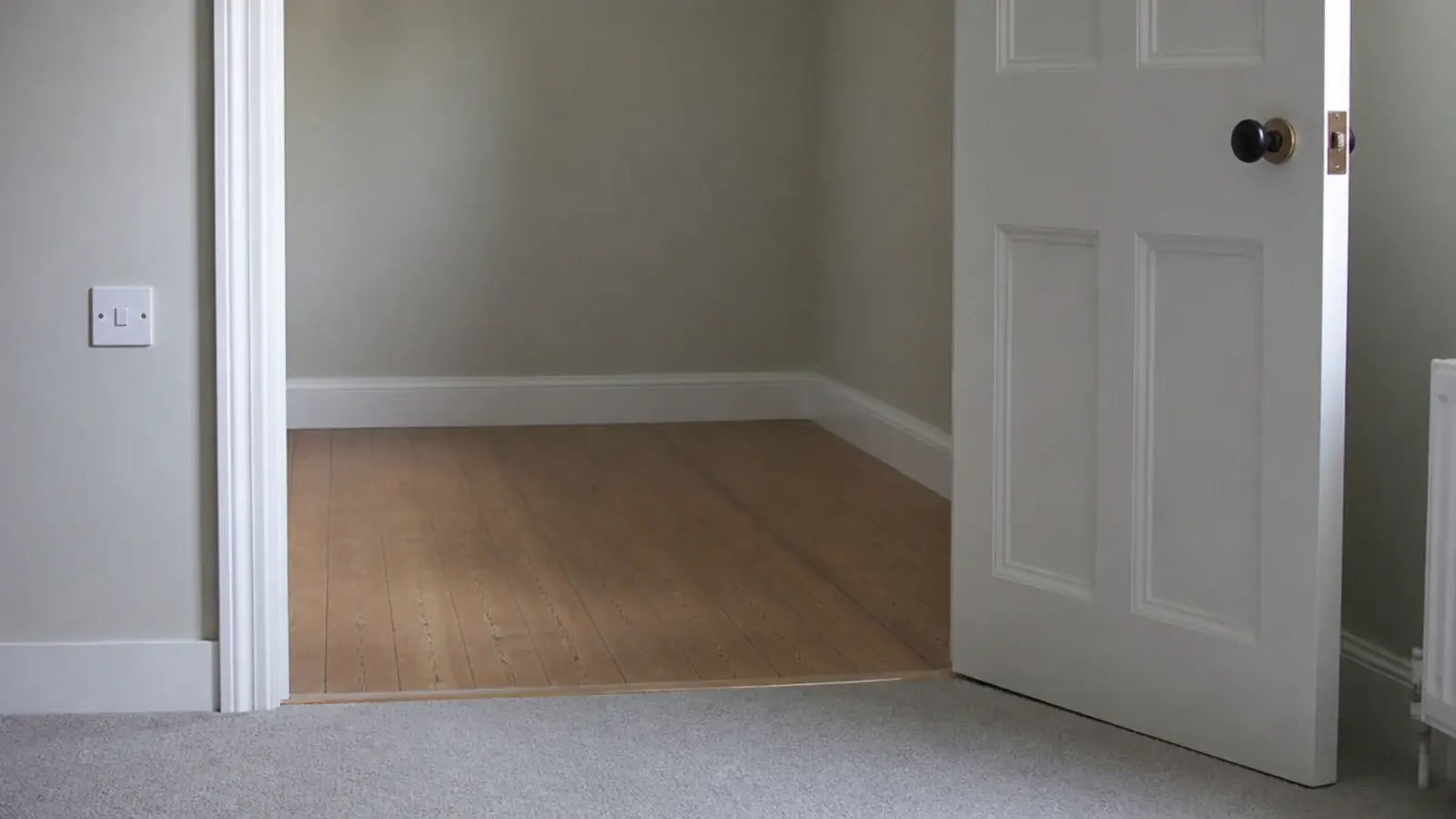 bedroom door standing open across an empty corner of a small room