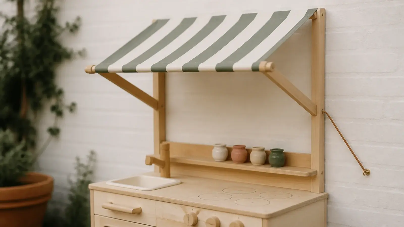 striped fabric awning fixed above a wooden play kitchen on a wall