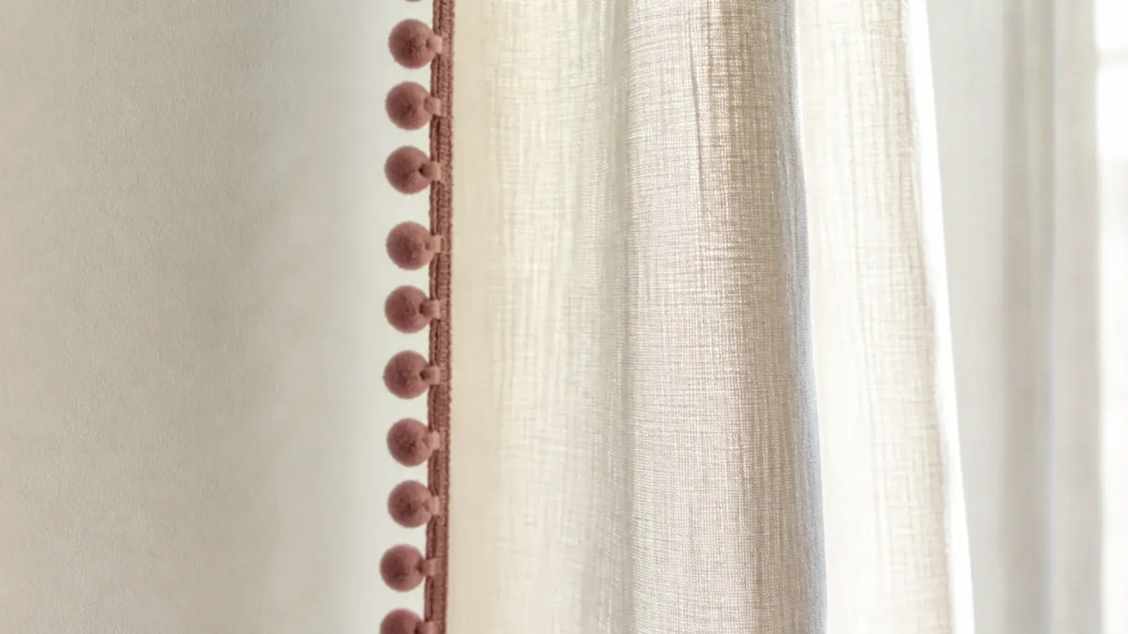 plain cream curtains finished with a small pom pom trim edge