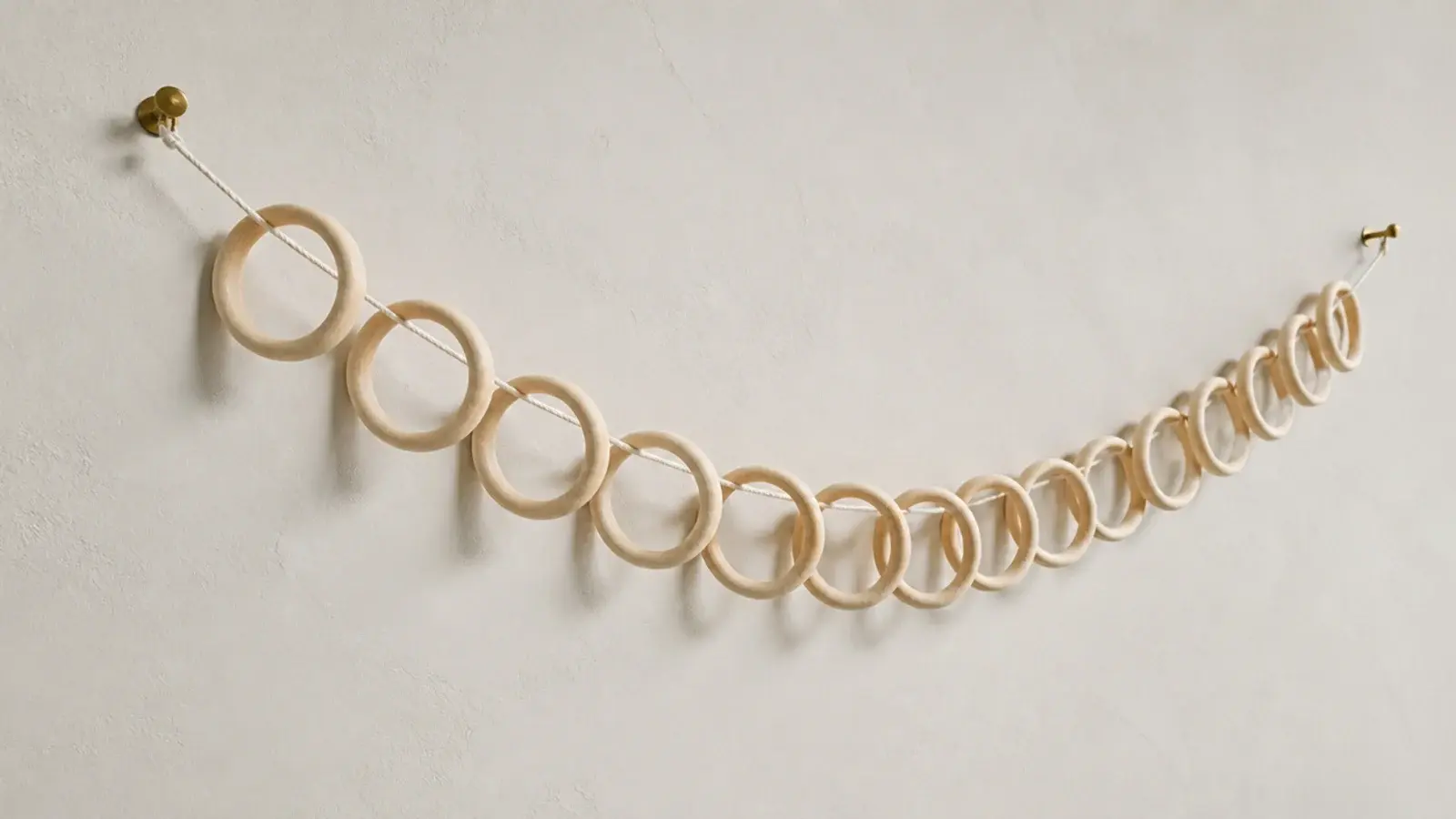 garland of pale wooden rings draped high across a bedroom wall