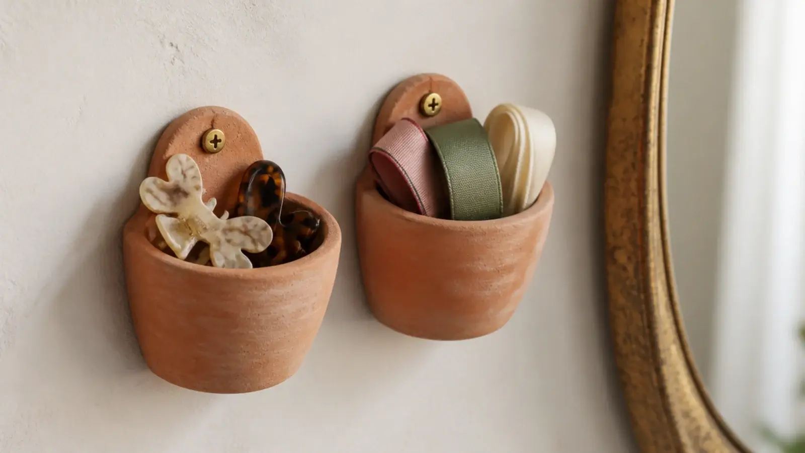 two small terracotta wall pots holding hair clips and ribbons