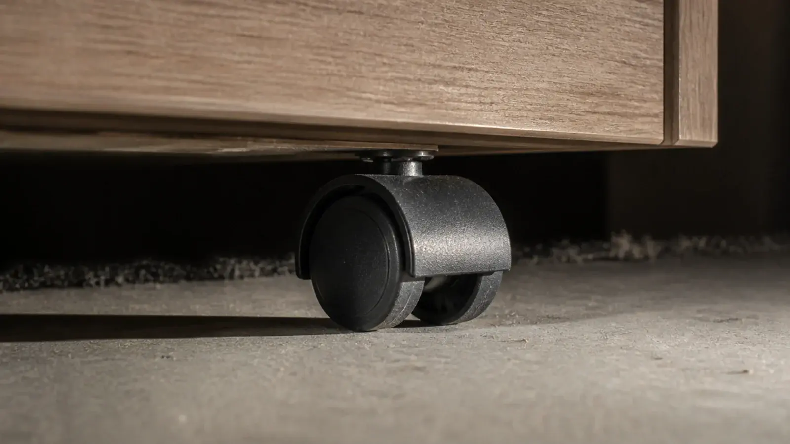 small black castor tucked under the base of a media cabinet