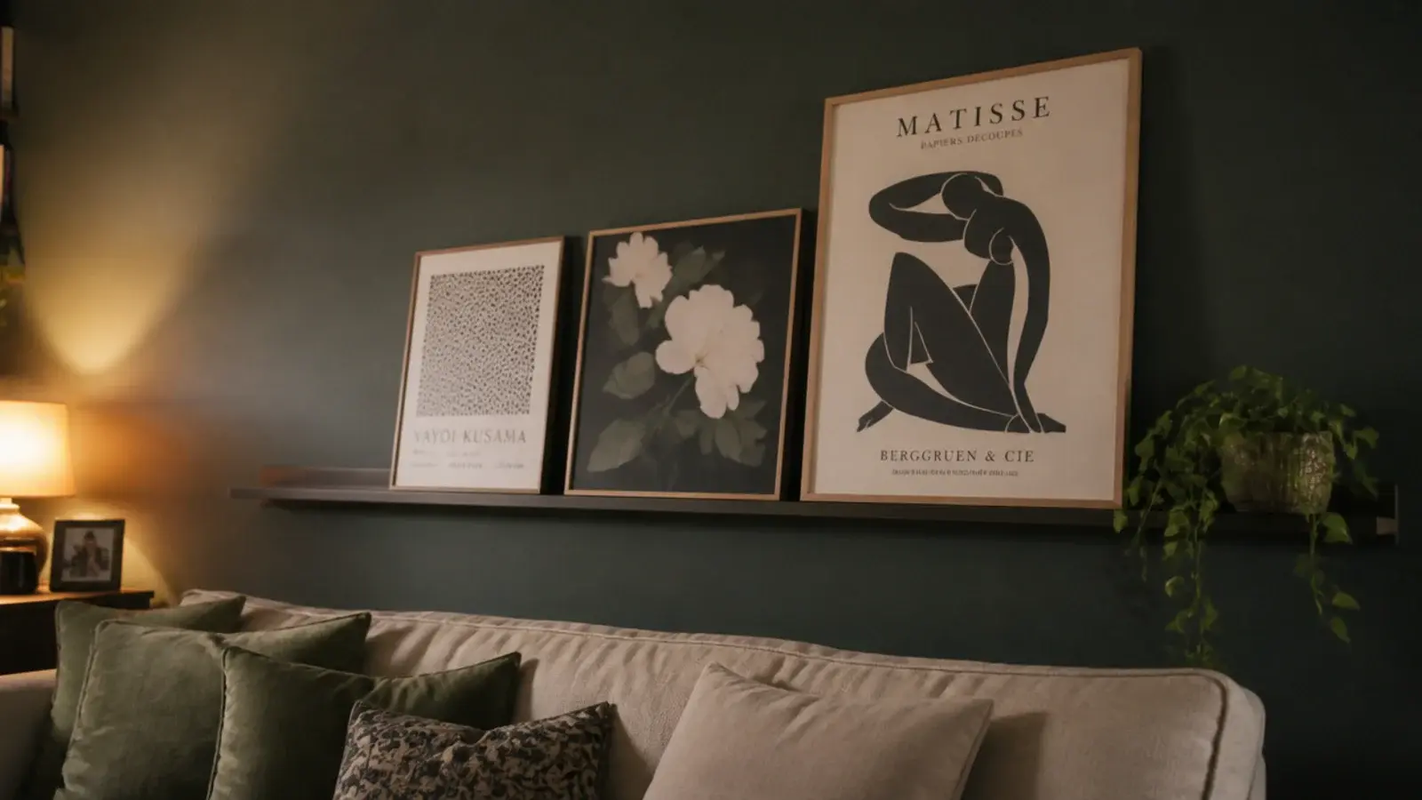 shallow picture ledge above a sofa holding leaning prints and a plant