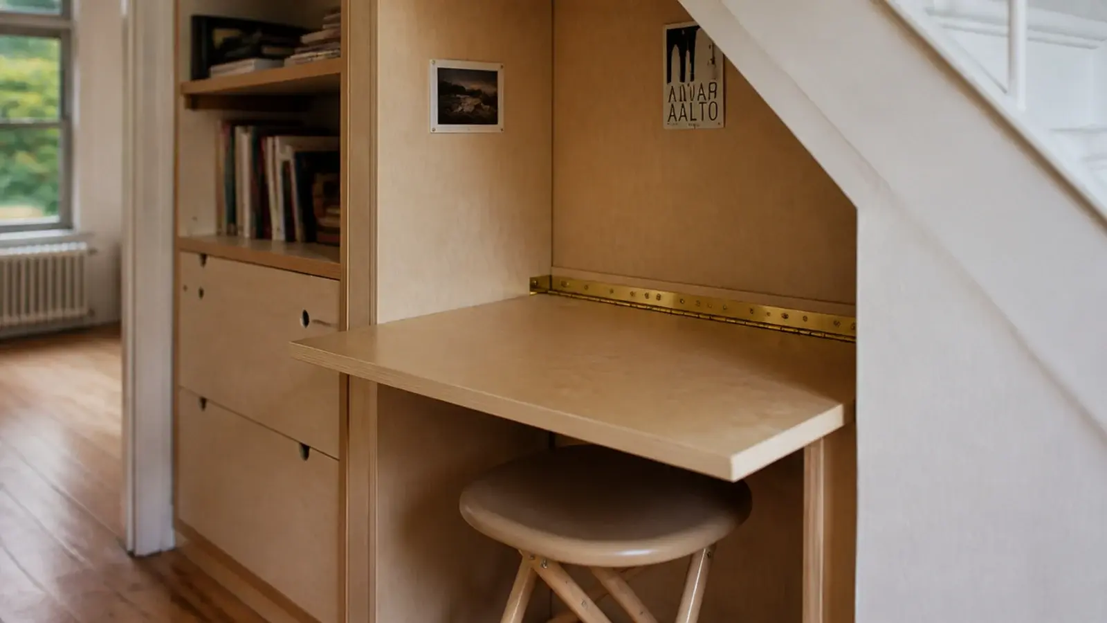 hinged plywood desk flap folded down against a tall stair wall