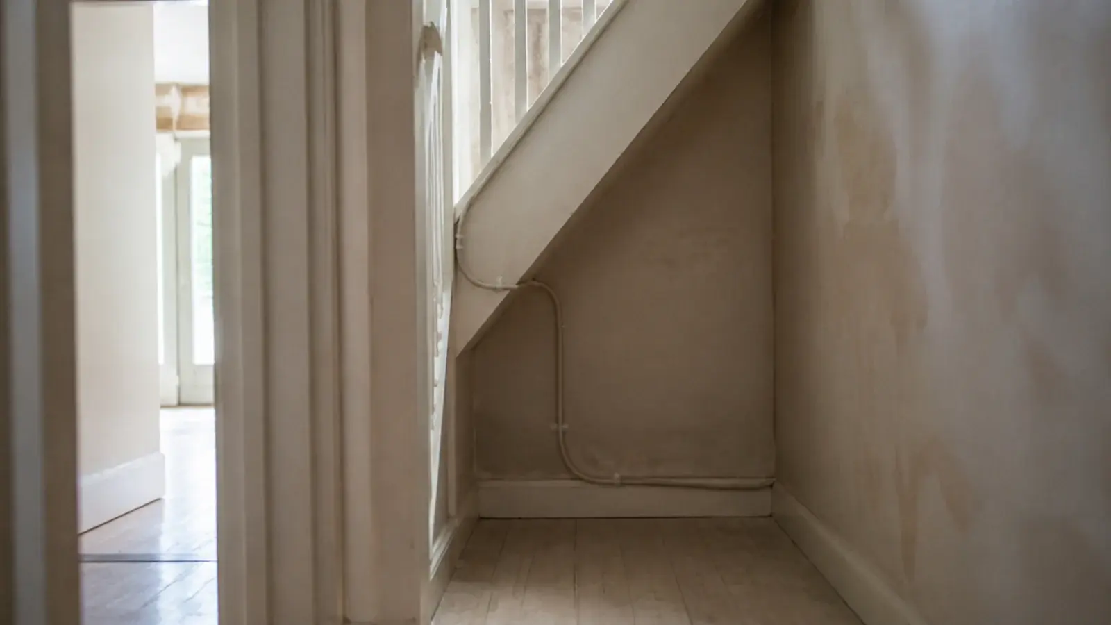 completely empty under stairs recess with bare plaster and floorboards