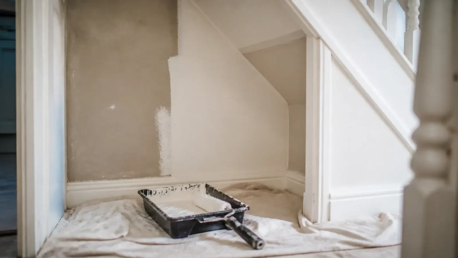 pale painted interior of an under stairs recess with a roller tray
