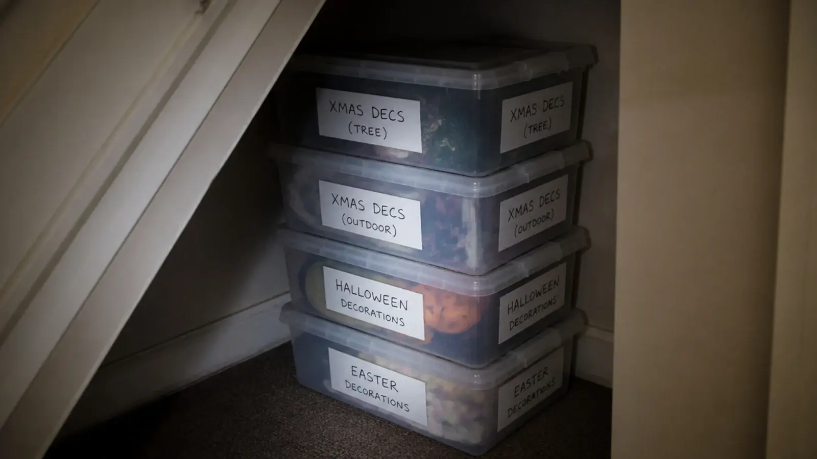 clear lidded boxes labelled on two faces stacked in a stair recess