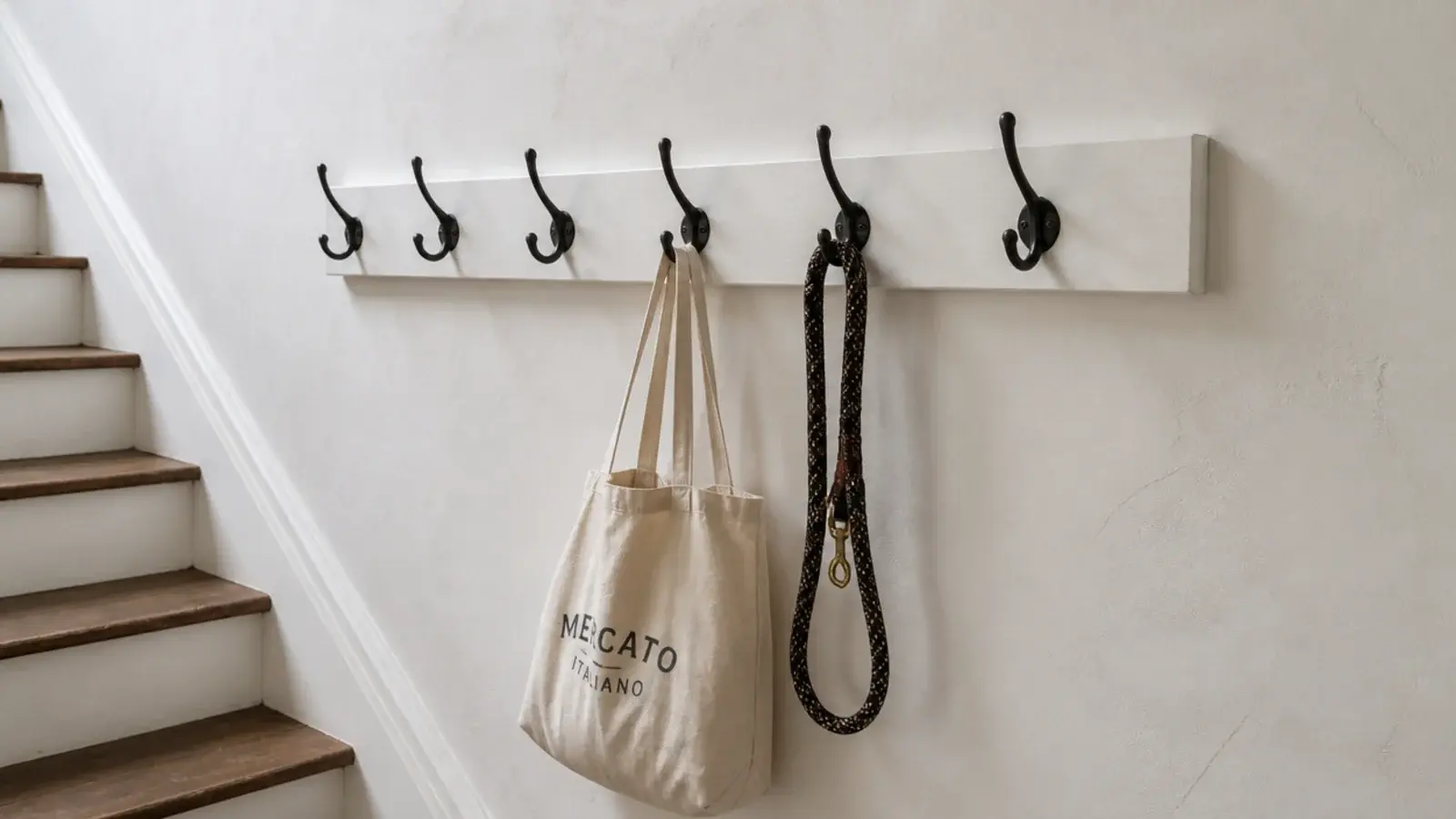 row of black hooks screwed to a batten on a staircase side wall