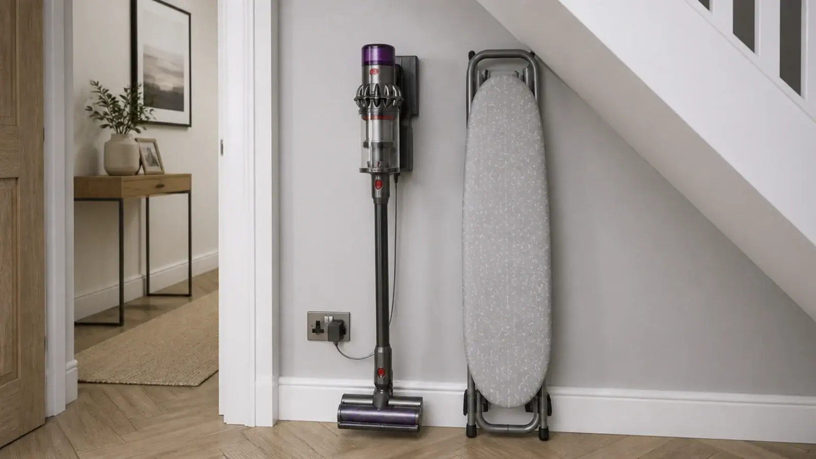 cordless vacuum docked on a wall bracket beneath a staircase soffit