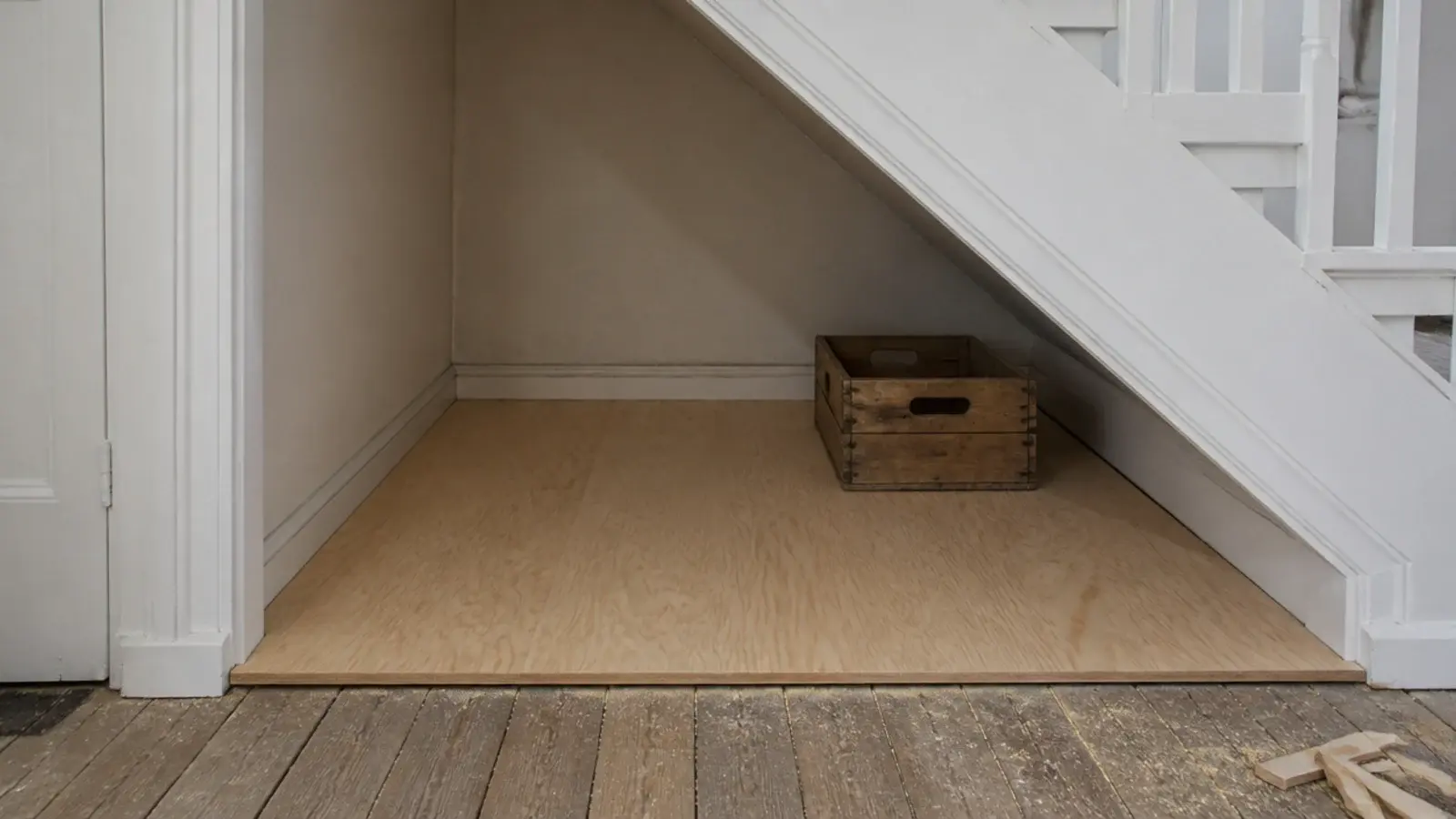 sheet of plywood laid as a flat base across an under stairs floor