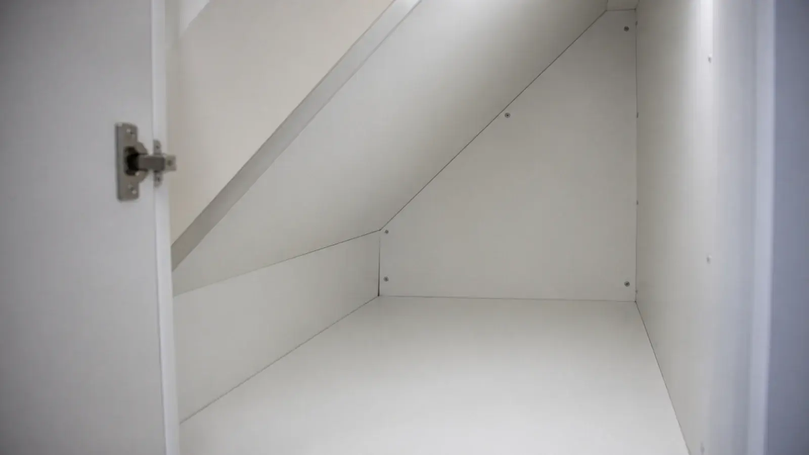 white melamine boards lining the sloping walls of a stairs cupboard
