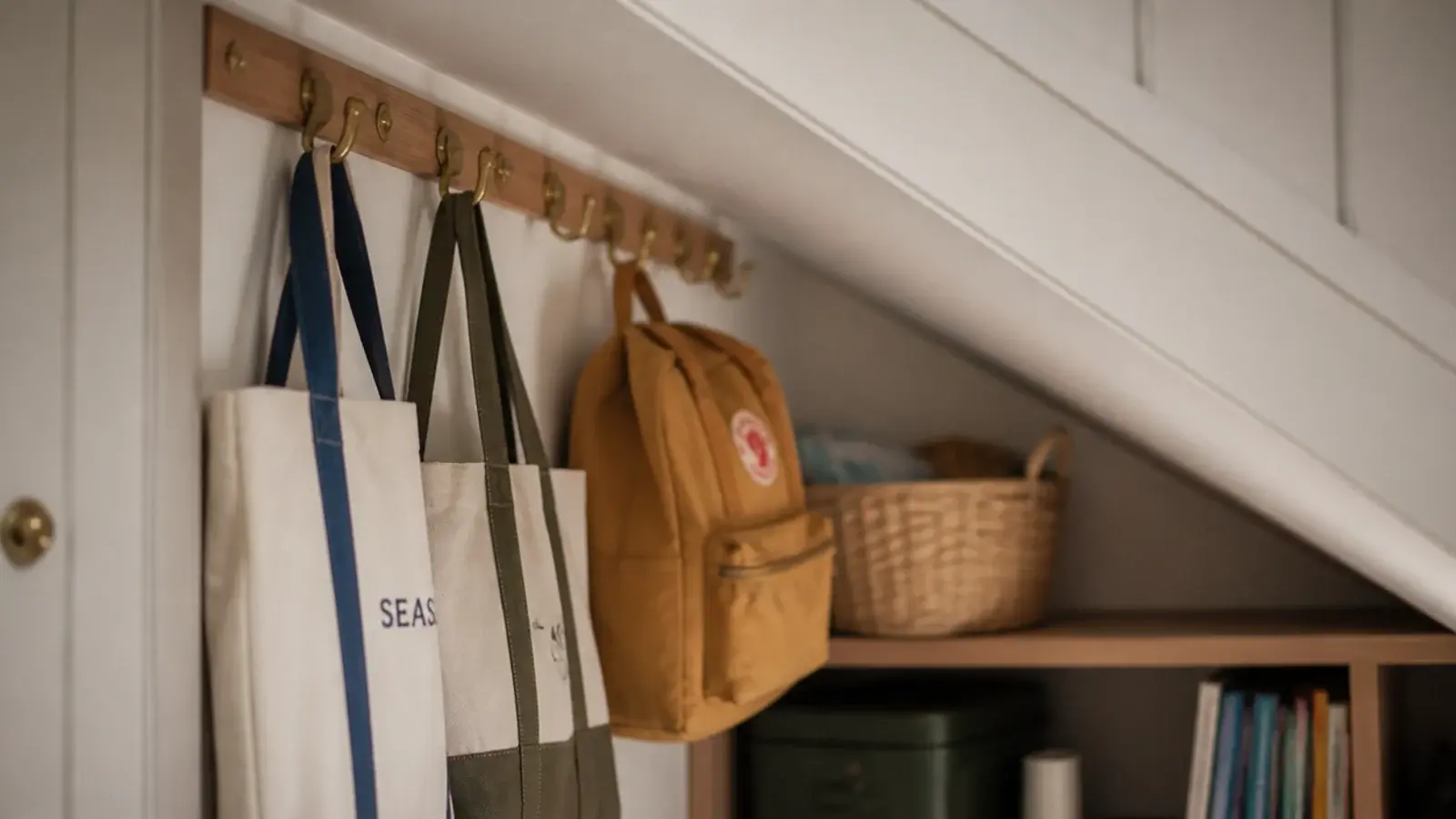 canvas bags hanging from hooks screwed into a stair soffit batten